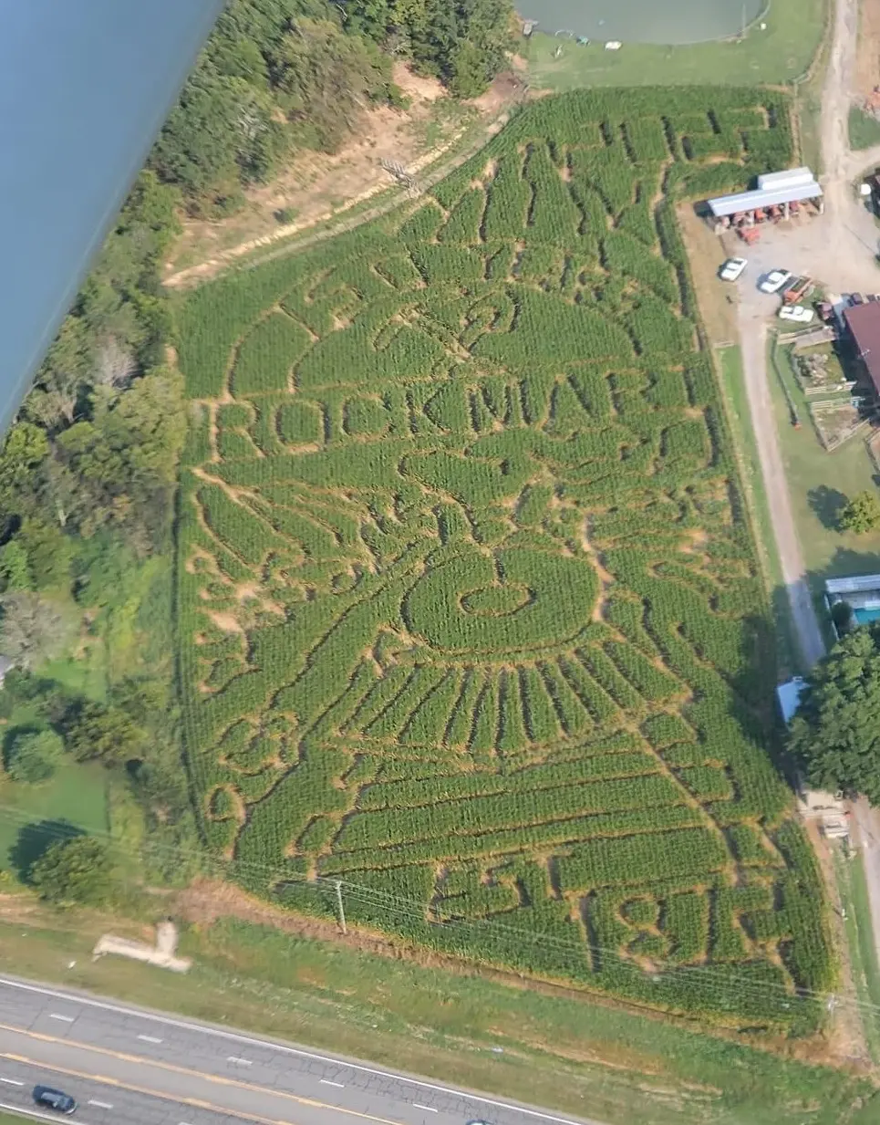 Aerial view of a corn maze celebrating 150 years of Rockmart, with a large clock tower and the year '1872' carved into the field.